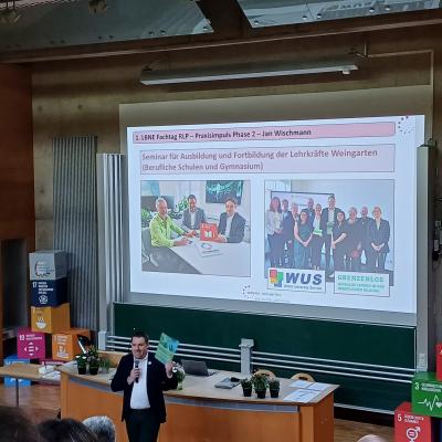 © WUS 2025 Ein Mann hält einen Vortrag vor einer großen Leinwand.